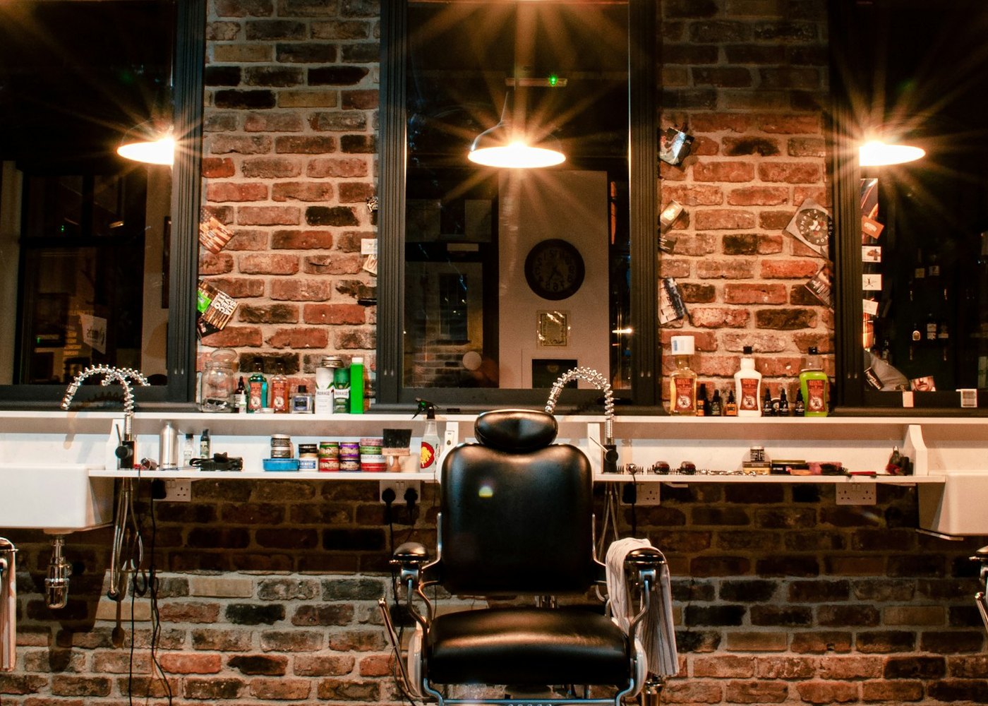 The row of barber's chairs and the mirrors along the brick wall, under the shop's pendant lamps